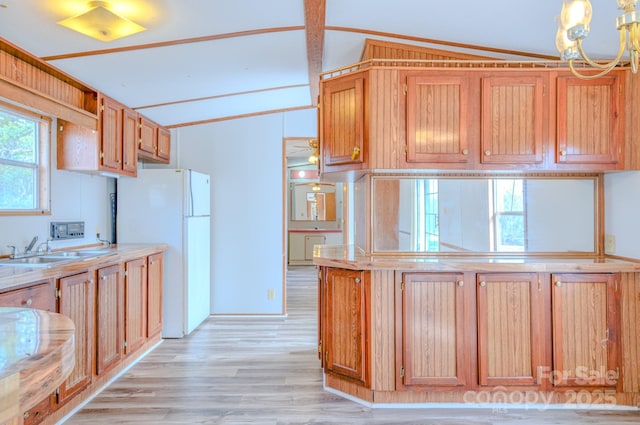 kitchen with lofted ceiling, a sink, light countertops, light wood-type flooring, and freestanding refrigerator