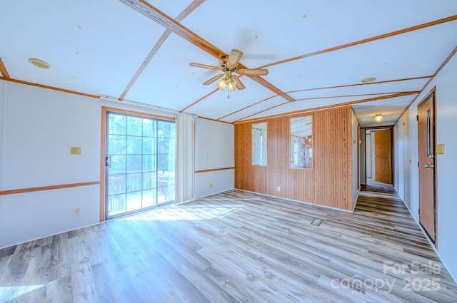 empty room with vaulted ceiling, light wood finished floors, and a ceiling fan