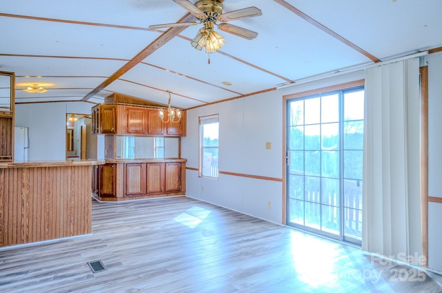 kitchen with brown cabinetry, freestanding refrigerator, a peninsula, light countertops, and light wood-style floors