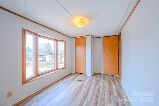 unfurnished bedroom featuring visible vents, a closet, light wood-style flooring, and crown molding