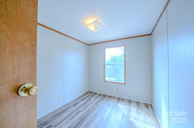 spare room featuring light wood finished floors and ornamental molding