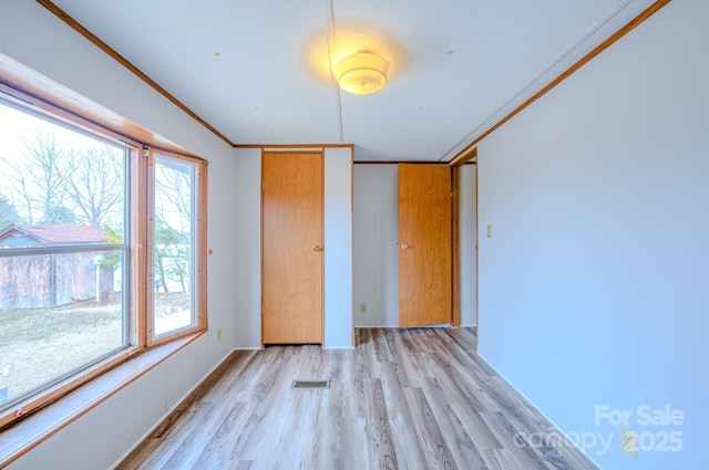 unfurnished bedroom with ornamental molding, visible vents, and light wood-style floors