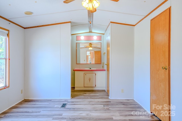 empty room featuring lofted ceiling, light wood-style flooring, visible vents, and ceiling fan