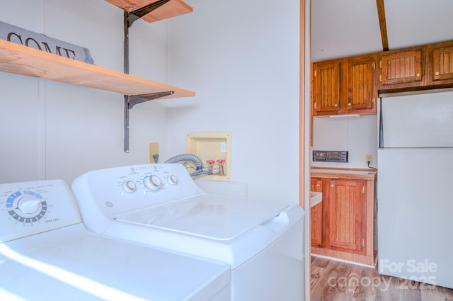 clothes washing area with laundry area, washer and clothes dryer, and light wood-type flooring