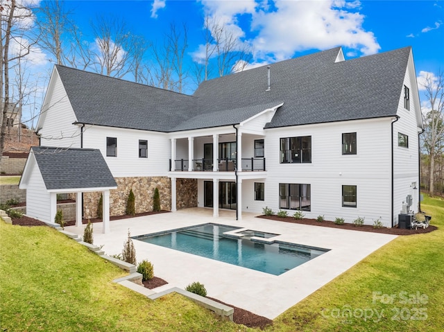 back of property featuring a patio, a yard, roof with shingles, and a balcony