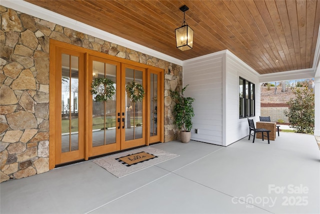 property entrance with stone siding, a porch, and french doors