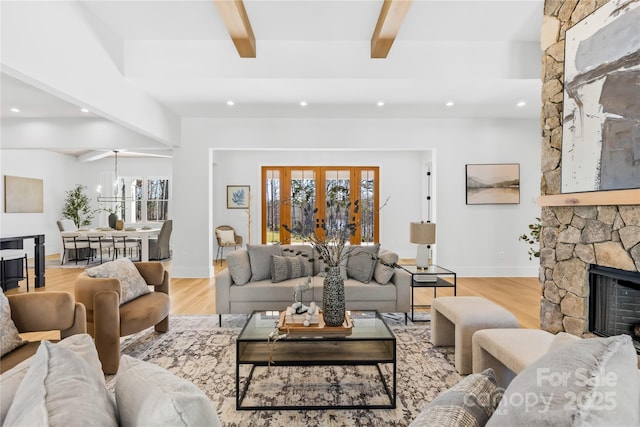 living area with beam ceiling, french doors, recessed lighting, a stone fireplace, and wood finished floors