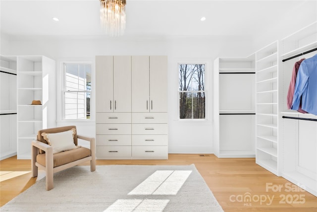 spacious closet with a chandelier and light wood finished floors