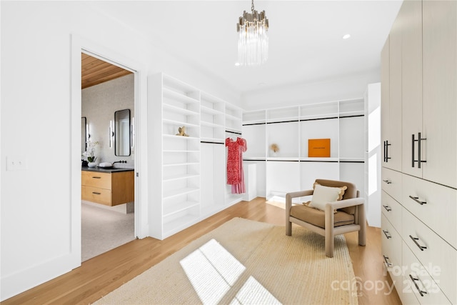 spacious closet featuring a notable chandelier, a sink, and light wood-style floors