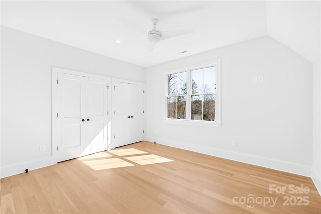 unfurnished bedroom featuring light wood finished floors, ceiling fan, baseboards, and multiple closets