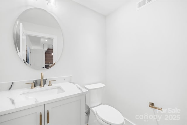 bathroom featuring toilet, visible vents, and vanity