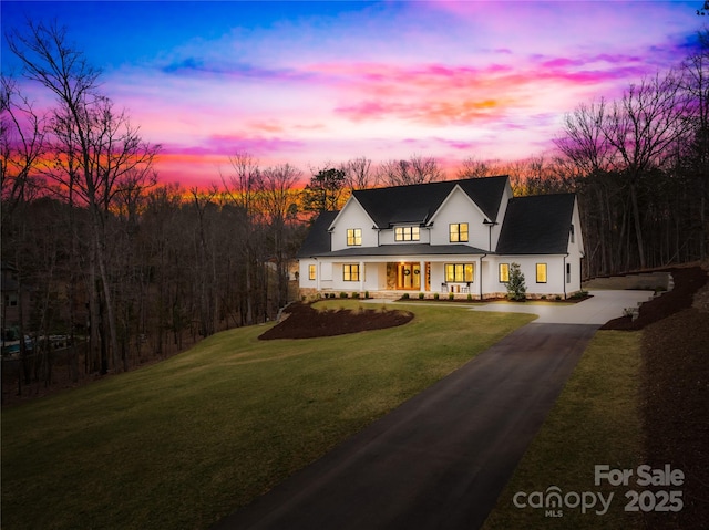 modern inspired farmhouse featuring aphalt driveway, covered porch, and a front lawn