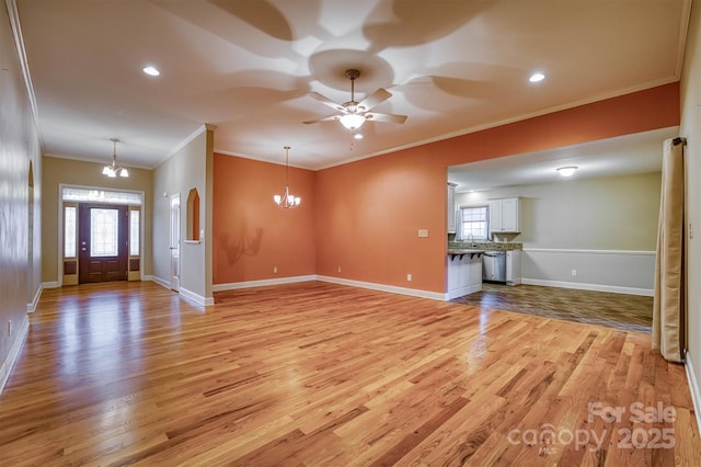 unfurnished living room featuring ceiling fan with notable chandelier, light wood finished floors, crown molding, and baseboards