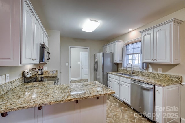 kitchen with stainless steel appliances, a peninsula, a sink, and white cabinets