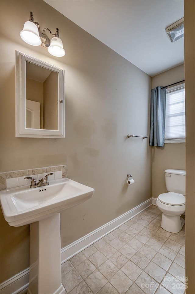 bathroom with toilet, baseboards, and a sink