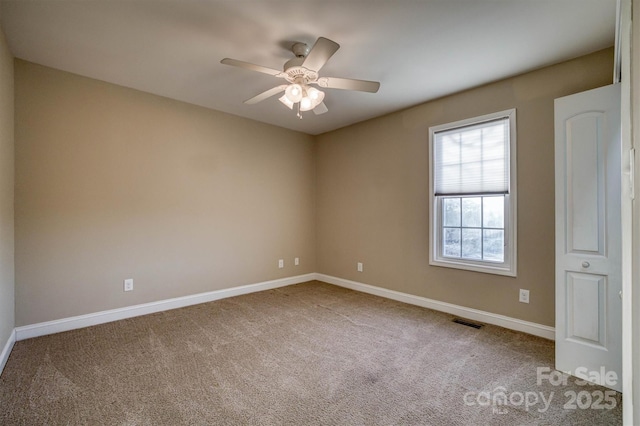 carpeted empty room with ceiling fan, visible vents, and baseboards