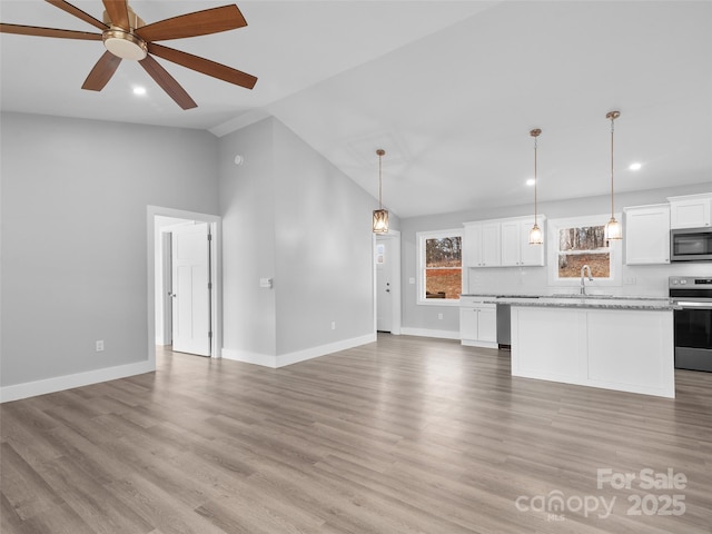 unfurnished living room with lofted ceiling, light wood-style flooring, baseboards, and a ceiling fan