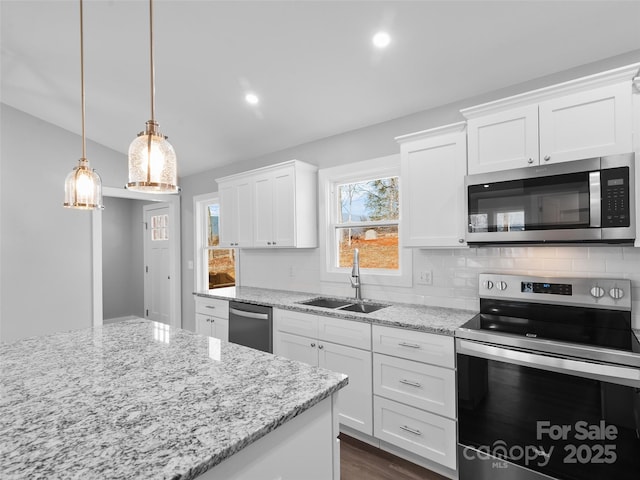 kitchen with appliances with stainless steel finishes, pendant lighting, white cabinetry, and a sink