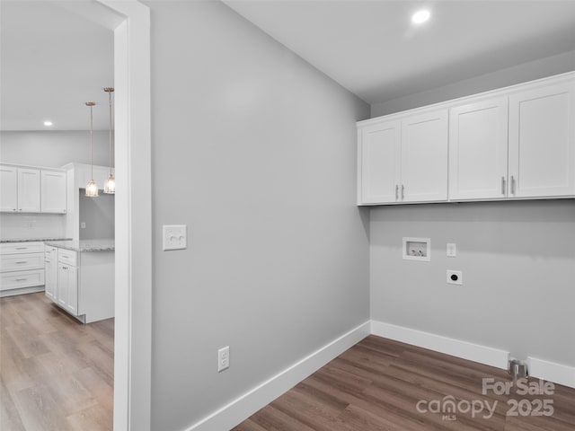 laundry room featuring hookup for a washing machine, hookup for an electric dryer, wood finished floors, baseboards, and cabinet space