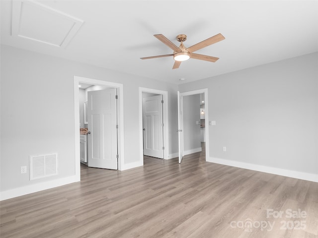 unfurnished room featuring baseboards, light wood-style flooring, visible vents, and attic access