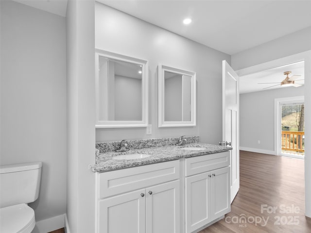 bathroom featuring ceiling fan, wood finished floors, a sink, and toilet