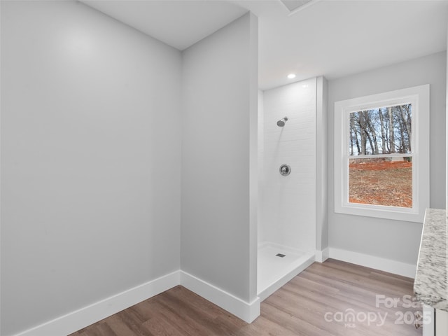 full bathroom featuring a tile shower, baseboards, and wood finished floors