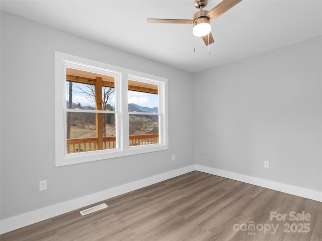 spare room with a ceiling fan, baseboards, visible vents, and wood finished floors