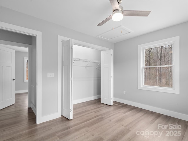 unfurnished bedroom with a closet, ceiling fan, light wood-style flooring, and baseboards