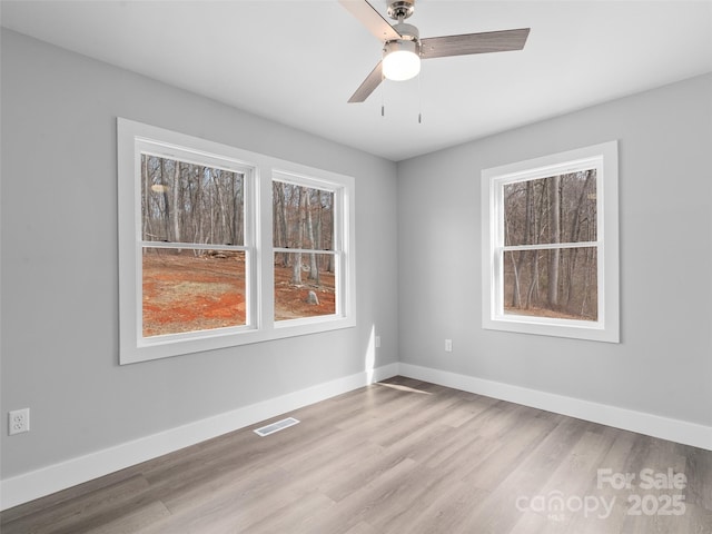 spare room with light wood-type flooring, baseboards, visible vents, and ceiling fan