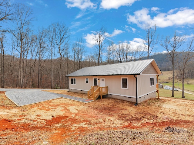 view of front of house featuring crawl space, metal roof, and driveway