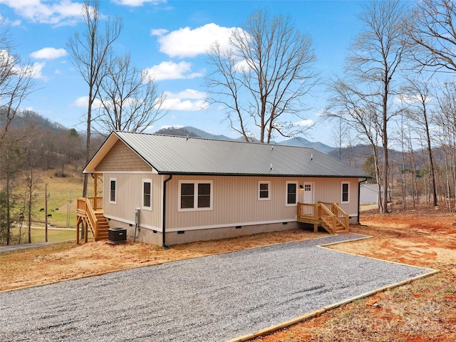 exterior space featuring stairway, crawl space, metal roof, a mountain view, and driveway