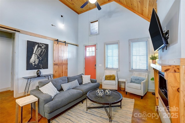 living area featuring a barn door, visible vents, a ceiling fan, wooden ceiling, and high vaulted ceiling