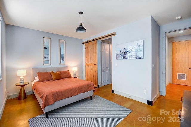 bedroom with visible vents, baseboards, and a barn door