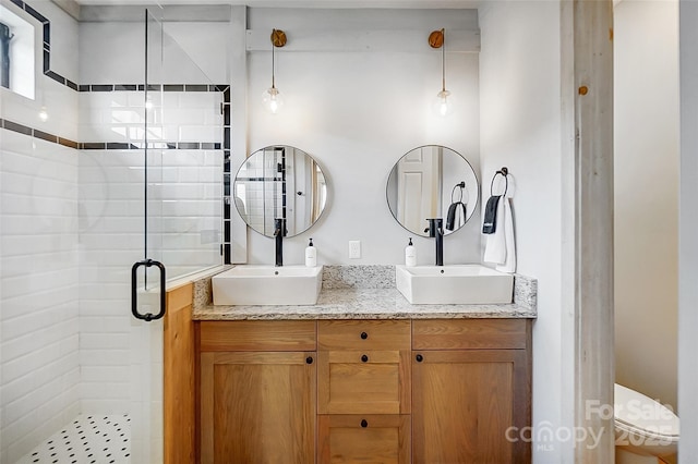 full bath with double vanity, a shower stall, and a sink