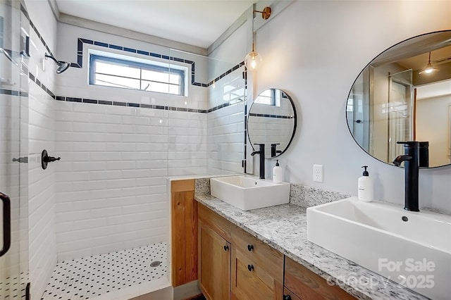 full bathroom featuring double vanity, a stall shower, and a sink