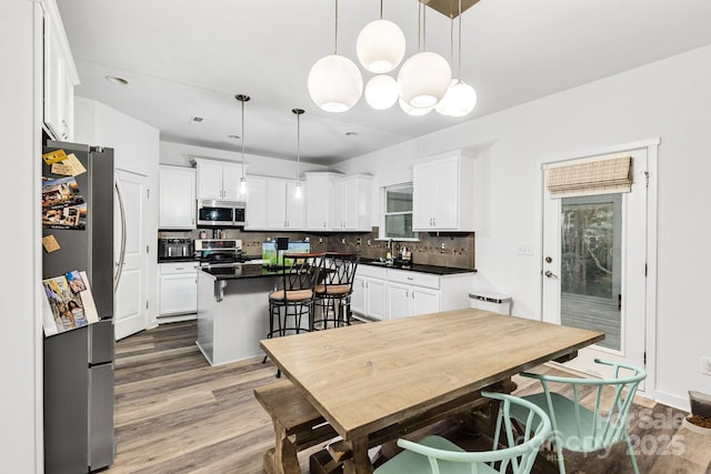 kitchen with appliances with stainless steel finishes, a kitchen island, white cabinetry, and tasteful backsplash