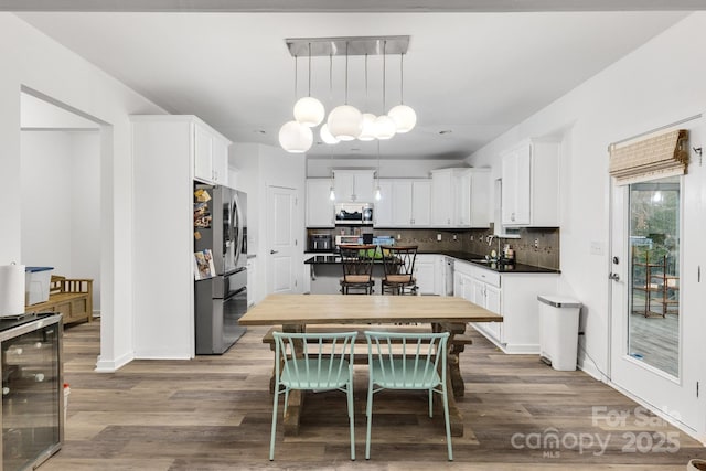 kitchen featuring beverage cooler, white cabinetry, stainless steel appliances, and wood finished floors