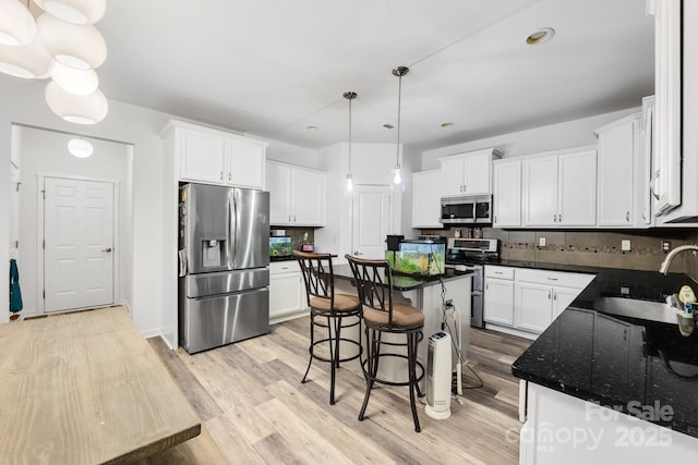 kitchen with appliances with stainless steel finishes, light wood-type flooring, a sink, and tasteful backsplash