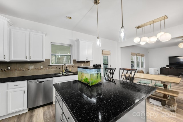 kitchen with dishwasher, a kitchen island, backsplash, white cabinetry, and a sink