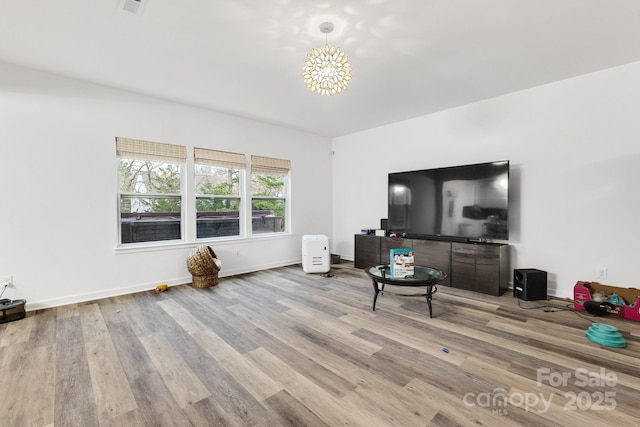 living room with a chandelier, wood finished floors, and baseboards