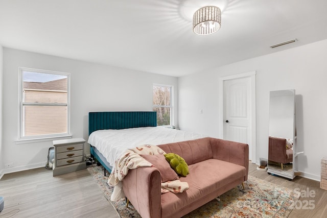 bedroom with light wood finished floors, visible vents, and baseboards