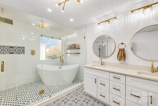 bathroom with a shower stall, double vanity, a sink, and tile patterned floors