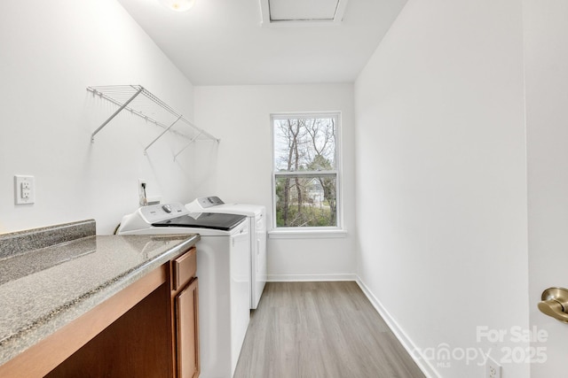 laundry area with light wood-style floors, baseboards, and washing machine and clothes dryer