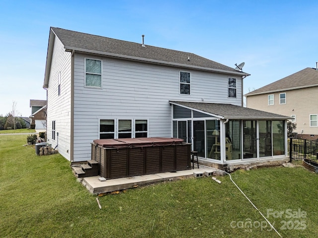 rear view of house featuring a sunroom, a hot tub, and a lawn