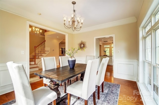 dining room featuring a notable chandelier, stairway, wainscoting, light wood finished floors, and crown molding