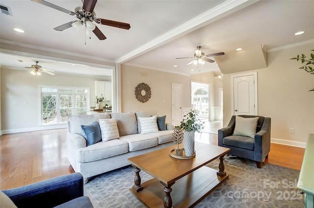 living room with crown molding, baseboards, and wood finished floors