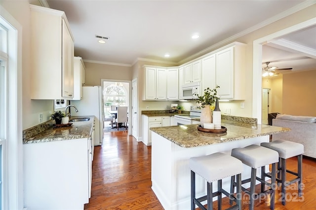 kitchen featuring crown molding, visible vents, a sink, white appliances, and a peninsula