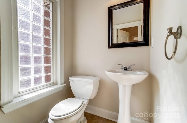 half bath featuring toilet and baseboards