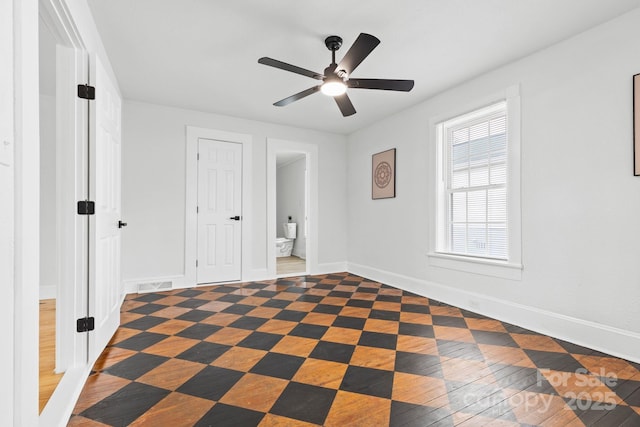 unfurnished bedroom featuring baseboards, visible vents, ensuite bathroom, and ceiling fan