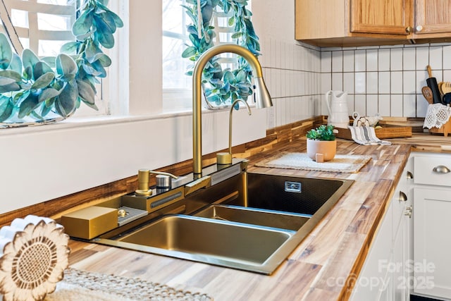 kitchen featuring butcher block countertops, backsplash, and a sink